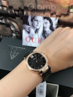 Montre Femme Guess W0638L5 tenue à la main, cadran noir texturé et boîtier or rose avec bracelet noir