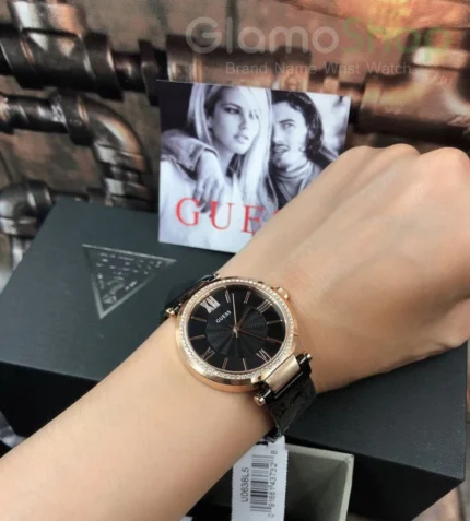 Montre Femme Guess W0638L5 tenue à la main, cadran noir texturé et boîtier or rose avec bracelet noir