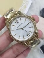Marque: Michael Kors Modèle: Whitney Boîtier: Diamètre : 3_mm Epaisseur : 8 mm Acier inoxydable Bronze Cadran: Verre : Minéral Bronze Bracelet: Acier inoxydable Bronze Etanchéité: 50 m (5 ATM) Type de boucle: Boucle déployant