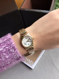 Montre Michael Kors Lexington Mini MK3229 dorée portée au poignet pour montrer sa taille de 26mm.