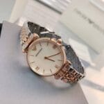 Détail de la montre femme nacre blanche Armani AR1683 bicolore or rose posée sur sa boîte au Maroc.