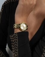 Vue rapprochée de la montre Guess femme dorée bracelet texturé GW0613L2 (34mm) sur un poignet, montrant les détails au Maroc.