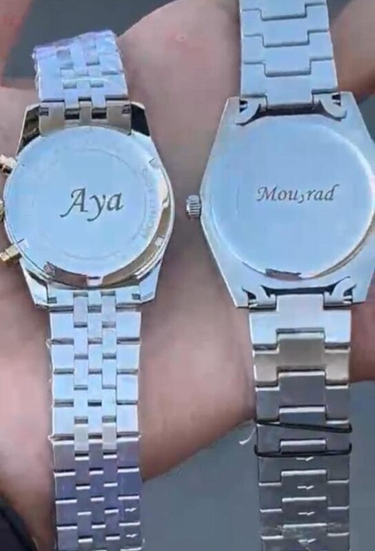 Vue de dos d'une montre à bracelet métallique avec une gravure personnalisée pour un couple, évoquant un cadeau partagé.