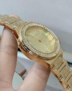 Profil de la montre Michael Kors MK7339 dorée, montrant la lunette à cristaux et la gravure "MK" sur le boîtier.