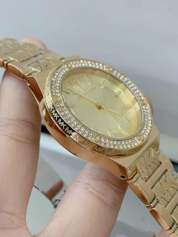 Profil de la montre Michael Kors MK7339 dorée, montrant la lunette à cristaux et la gravure "MK" sur le boîtier.