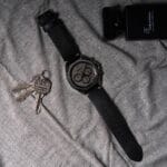 Vue rapprochée de la montre Hugo Boss Cloud 1514014 posée sur un tissu gris, montrant les détails du cadran, les aiguilles noires et les poussoirs du chronographe.