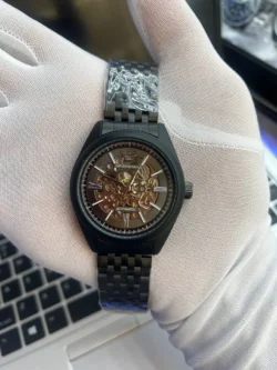 Montre homme Emporio Armani AR60093 automatique à cadran skeleton noir tenue dans une main gantée