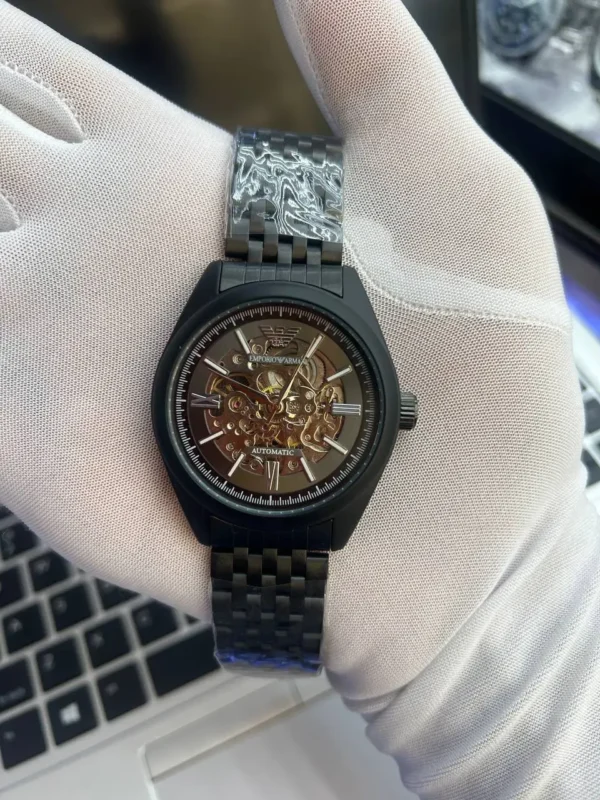 Montre homme Emporio Armani AR60093 automatique à cadran skeleton noir tenue dans une main gantée