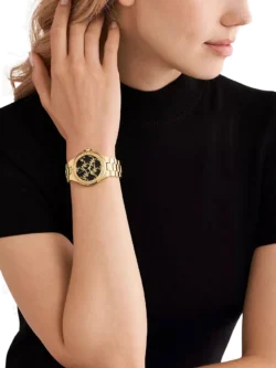 Michael Kors MK7404 portée au poignet d'une femme, bracelet doré et cadran noir élégant