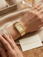 Montre Guess GW0874L4 portée au poignet d'une femme, boîtier rectangle doré