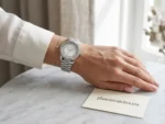 Montre Michael Kors argentée portée au poignet d’une femme avec carte Planetawatches.ma