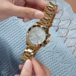 Montre Guess GW0696L2 Phoebe femme tenue entre deux mains, cadran bleu clair soleillé et index dorés