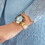 Montre Guess GW0696L2 femme portée de profil au poignet, cadran bleu clair et bracelet à maillons dorés