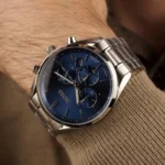 Montre Hugo Boss 1513818 Champion portée au poignet avec un pull beige, cadran bleu et boîtier en acier