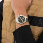 Montre Hugo Boss 1514267 Hero 2.0 portée au poignet avec un gilet beige et un haut noir, cadran noir