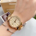 Montre Michael Kors MK3235 Nini femme portée au poignet, cadran champagne à index sertis de cristaux