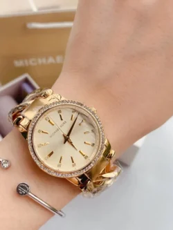 Montre Michael Kors MK3235 Nini femme portée au poignet, cadran champagne à index sertis de cristaux