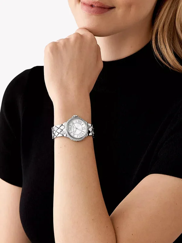 Montre Michael Kors MK4804 Camille portée au poignet d'une femme en haut noir, boîtier argenté serti de cristaux