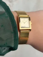 Élégante montre Michael Kors MK4959 carrée en acier doré portée au poignet par une femme