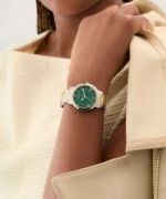 Montre Guess GW0404L5 Dawn femme bicolore portée au poignet, cadran vert, avec veste beige