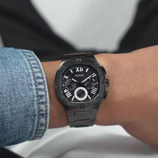 Montre Guess GW0572G3 Headline noire portée au poignet d'un homme, à côté d'une manche en jean