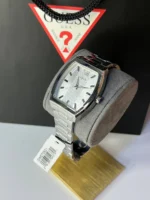 Montre Guess GW0705G1 homme sur un coussin gris devant un sac Guess, étiquette de référence visible