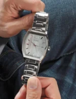 Montre Guess GW0705G1 homme tenue entre les doigts, cadran argenté texturé et bracelet acier brillant
