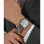 Montre Guess GW0705G1 homme portée au poignet avec costume gris et chemise blanche, cadran argenté