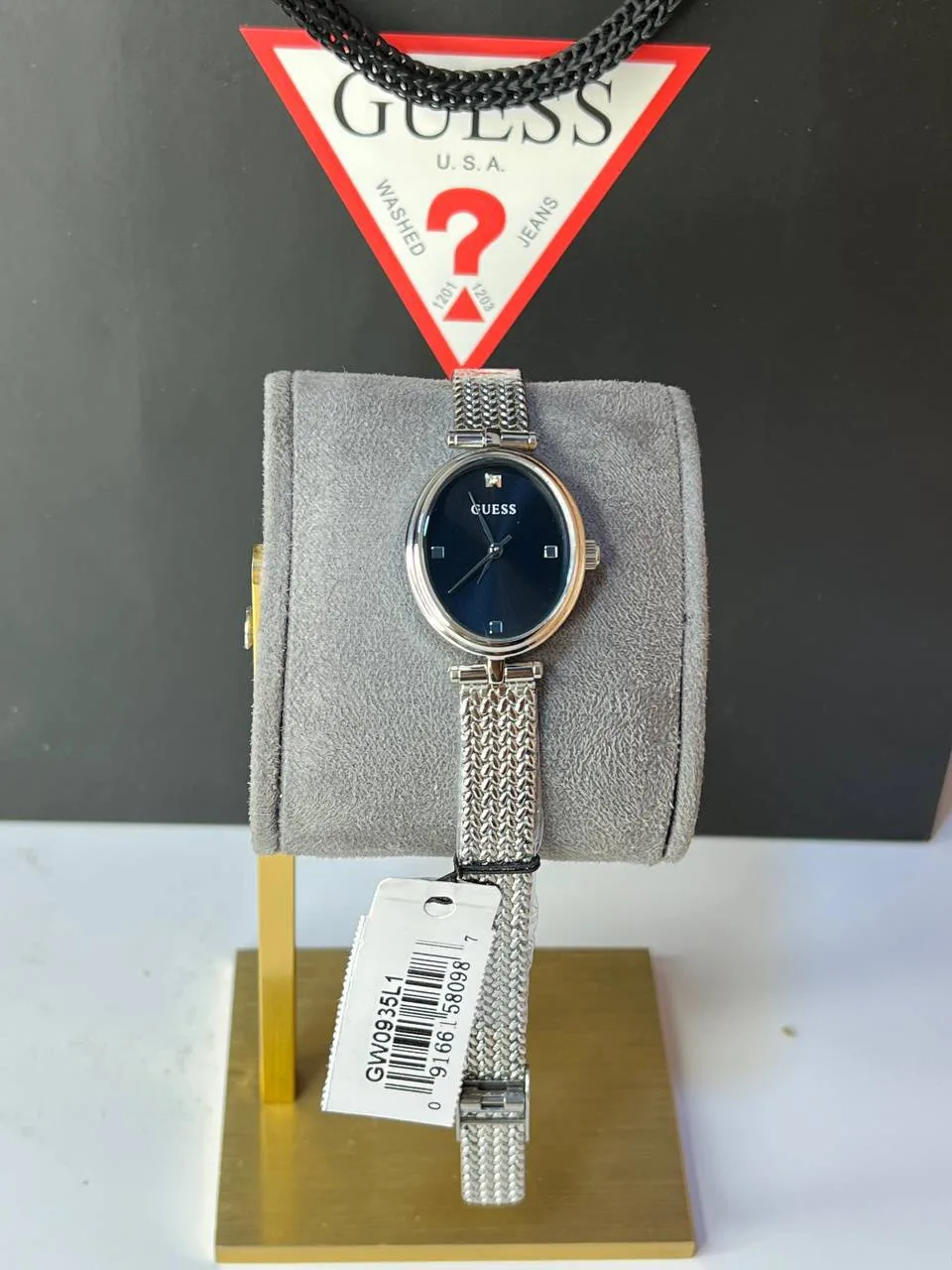 Montre Guess GW0935L1 femme neuve sur présentoir gris avec étiquette, cadran sombre et bracelet argenté