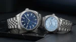 Duo de montres Guess GW0977G1 homme et GW0936L1 femme posées côte à côte, lunettes cannelées et bracelets jubilé