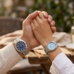 Couple, mains jointes sur une terrasse, portant la montre Guess GW0977G1 homme et la Guess GW0936L1 femme