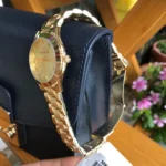 Michael Kors MK3456 vue de profil posée sur un sac bleu marine, couronne dorée et fermoir déployant ouvert