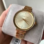 Montre Michael Kors MK3792 posée sur un présentoir, cadran doré et bracelet acier doré