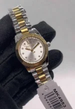 Michael Kors MK4953 tenue dans une main gantée de noir avec son étiquette, cadran argenté à index en cristaux