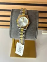 Michael Kors MK4953 posée sur un coussin présentoir gris avec son étiquette, lunette dorée et cadran argenté