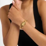 Femme en débardeur noir portant la Michael Kors MK4957 dorée au poignet, bracelet à larges anneaux ovales