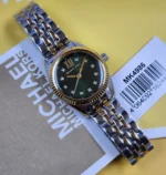 Montre Michael Kors MK4986 Lexington vue de face avec son étiquette, cadran vert à cristaux et lunette dorée