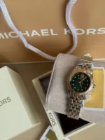 Michael Kors MK4986 posée sur le coussin de son écrin, cadran vert émeraude et bracelet bicolore argent et or