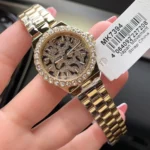 Montre Michael Kors MK7394 tenue dans la main avec son étiquette, cadran léopard et bracelet en acier doré