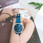 Michael Kors MKO1004 posée sur un magazine, cadran bleu chronographe et étiquettes de la marque encore attachées au bracelet.
