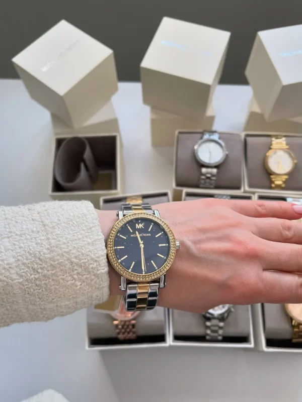 Montre Michael Kors MKO1049 femme portée au poignet, cadran bleu nuit, lunette dorée pavée et bracelet bicolore