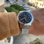 Montre Tommy Hilfiger 1792104 Troy homme portée au poignet avec un pull camel, cadran bleu et bracelet acier